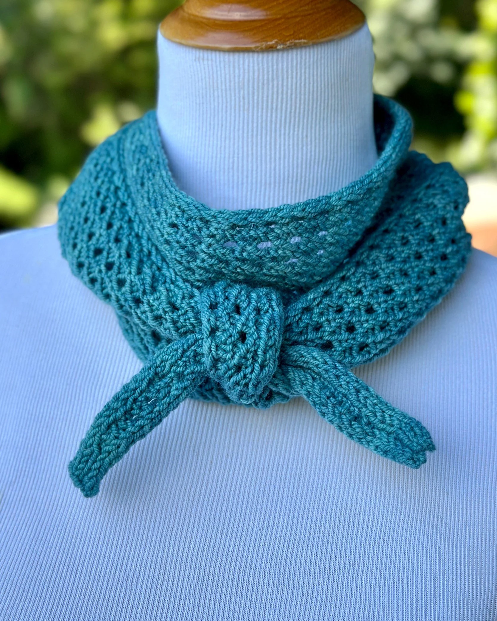 Moonbeam Scarf, an easy textured lace knitting pattern, is loosely knotted in front for a casual look.