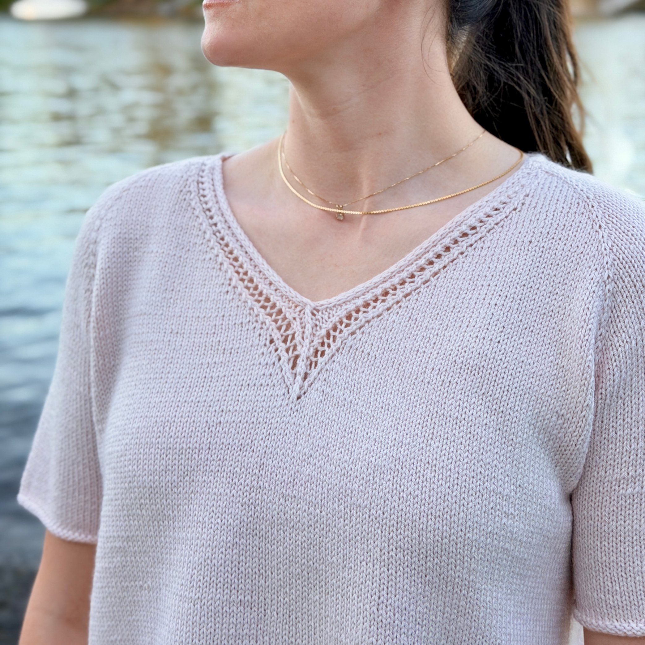 Classic Lace Tee, a V-Neck Knit Top / Pullover / Sweater Pattern in a blush colored yarn by Rosy Green Wool on model in front of river