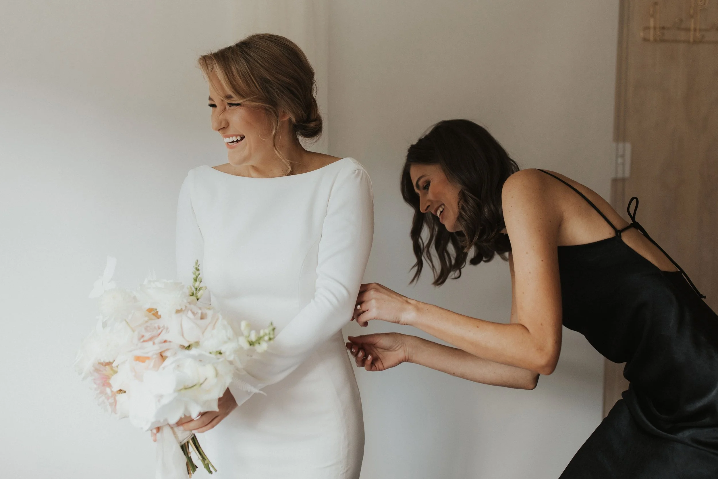 bridesmaid-helping-happy-bride-with-wedding-dress.jpg