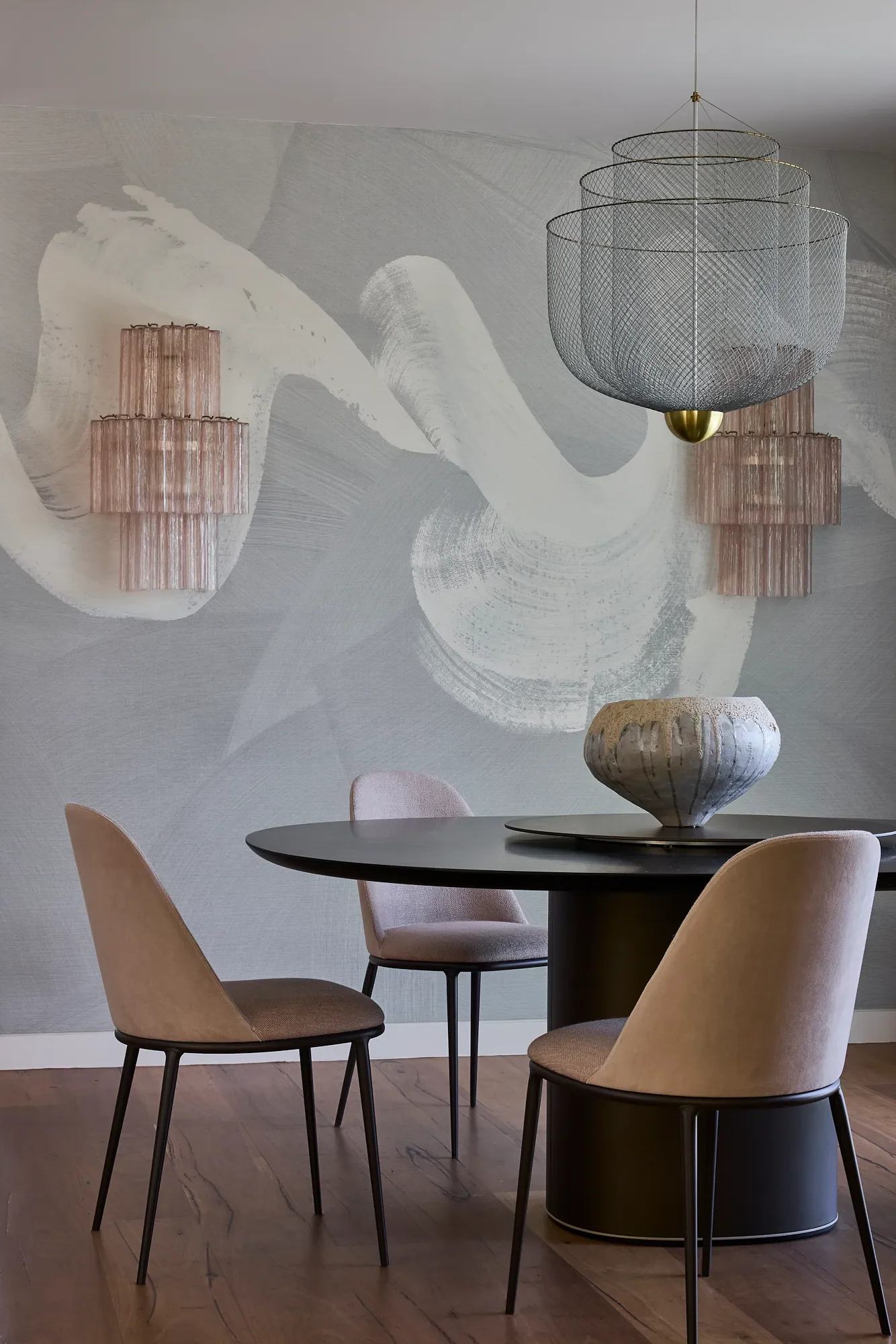 Dining area in Balmoral Reverie, with baby pink glass chandeliers and textured grey wallpaper