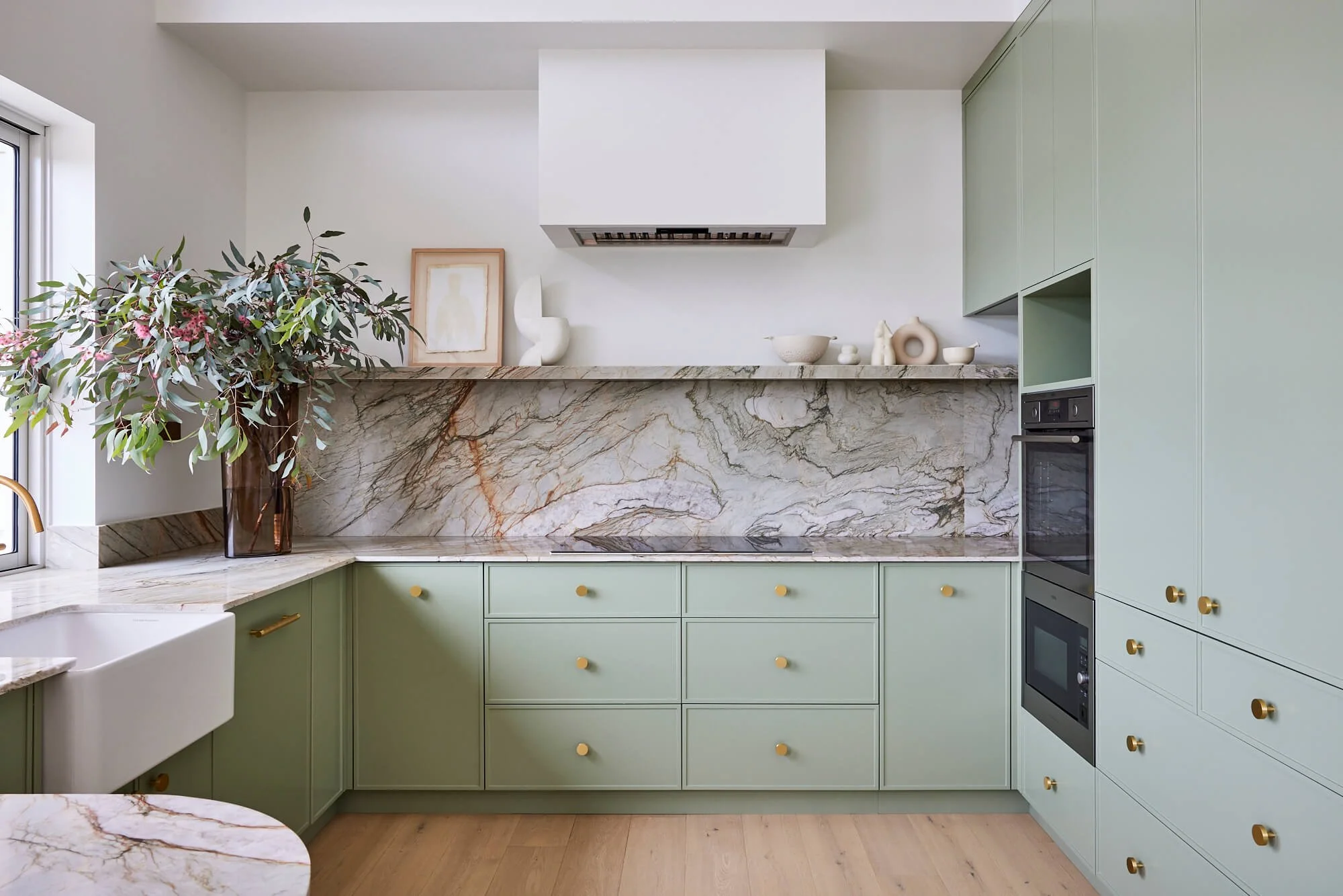 Kitchen with pale green cabinets and marble splash back