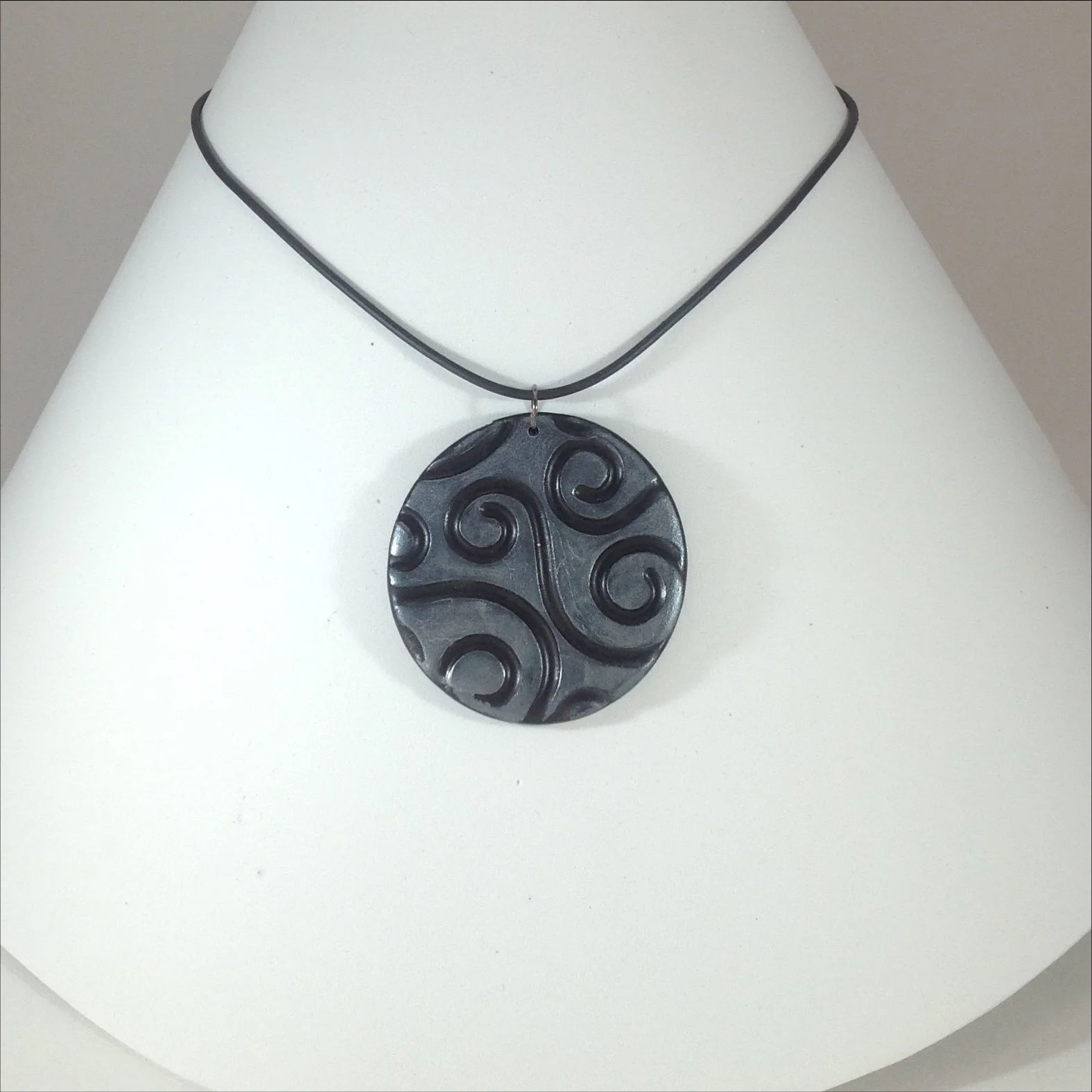 black polymer clay round pendant with silver design on stand