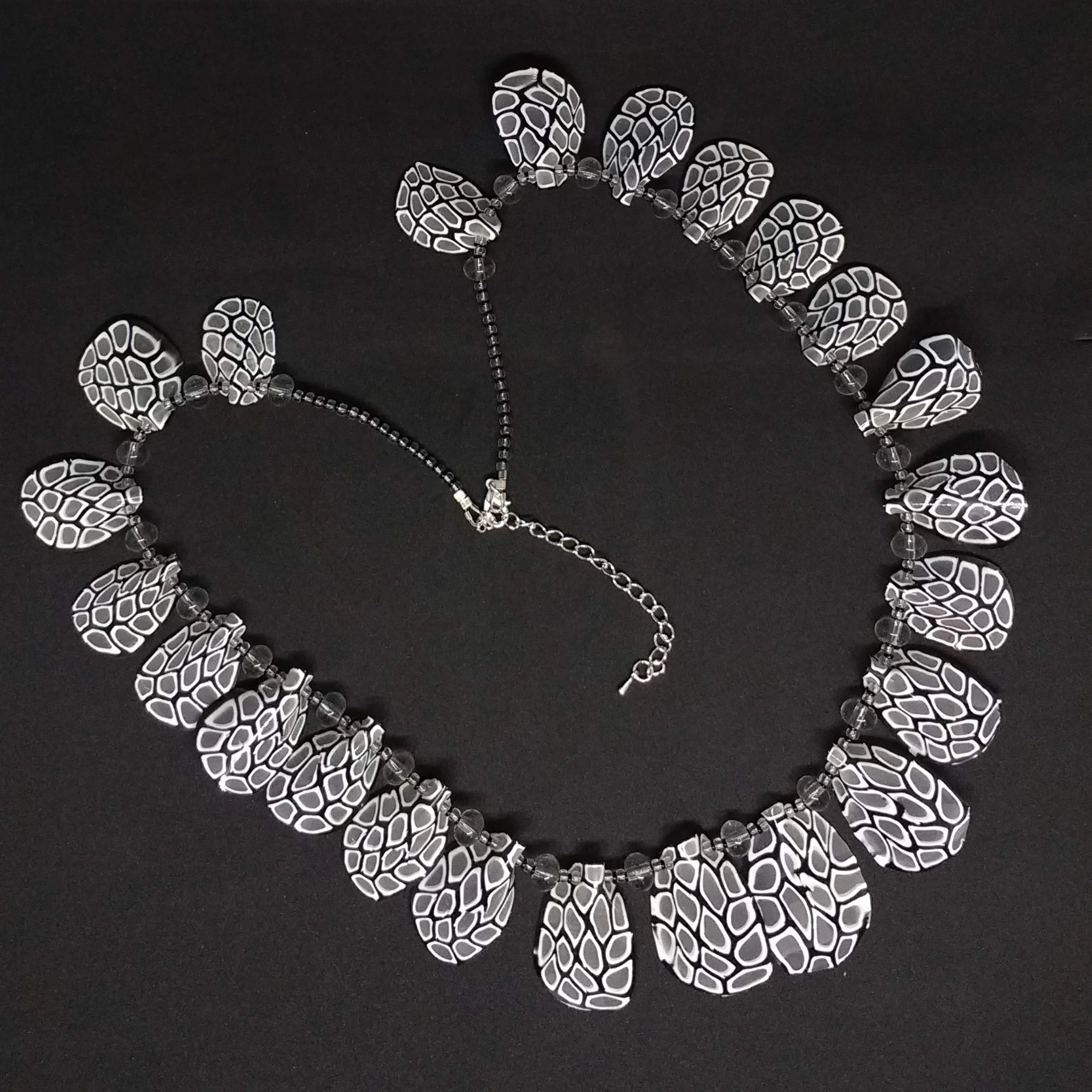 Polymer clay black and white petal shapes necklace on black background