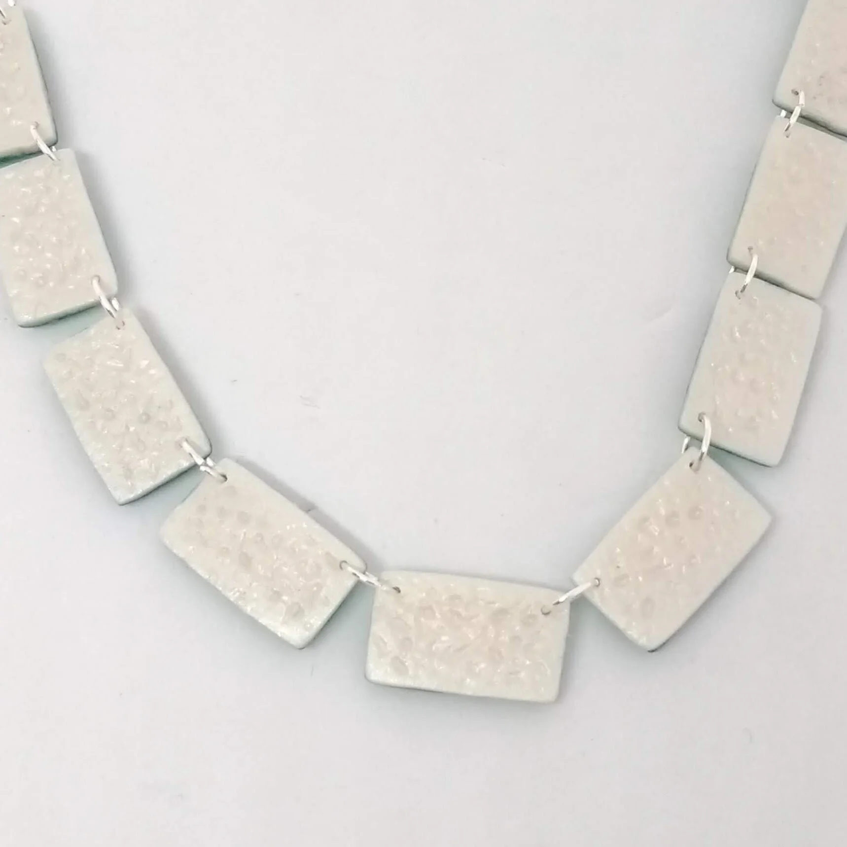Back detail of polymer clay necklace with oblong beads with bright coloured design