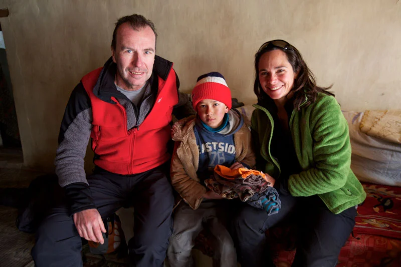 Rolf and Pascale gifting clothes to a young boy in Rumbak.