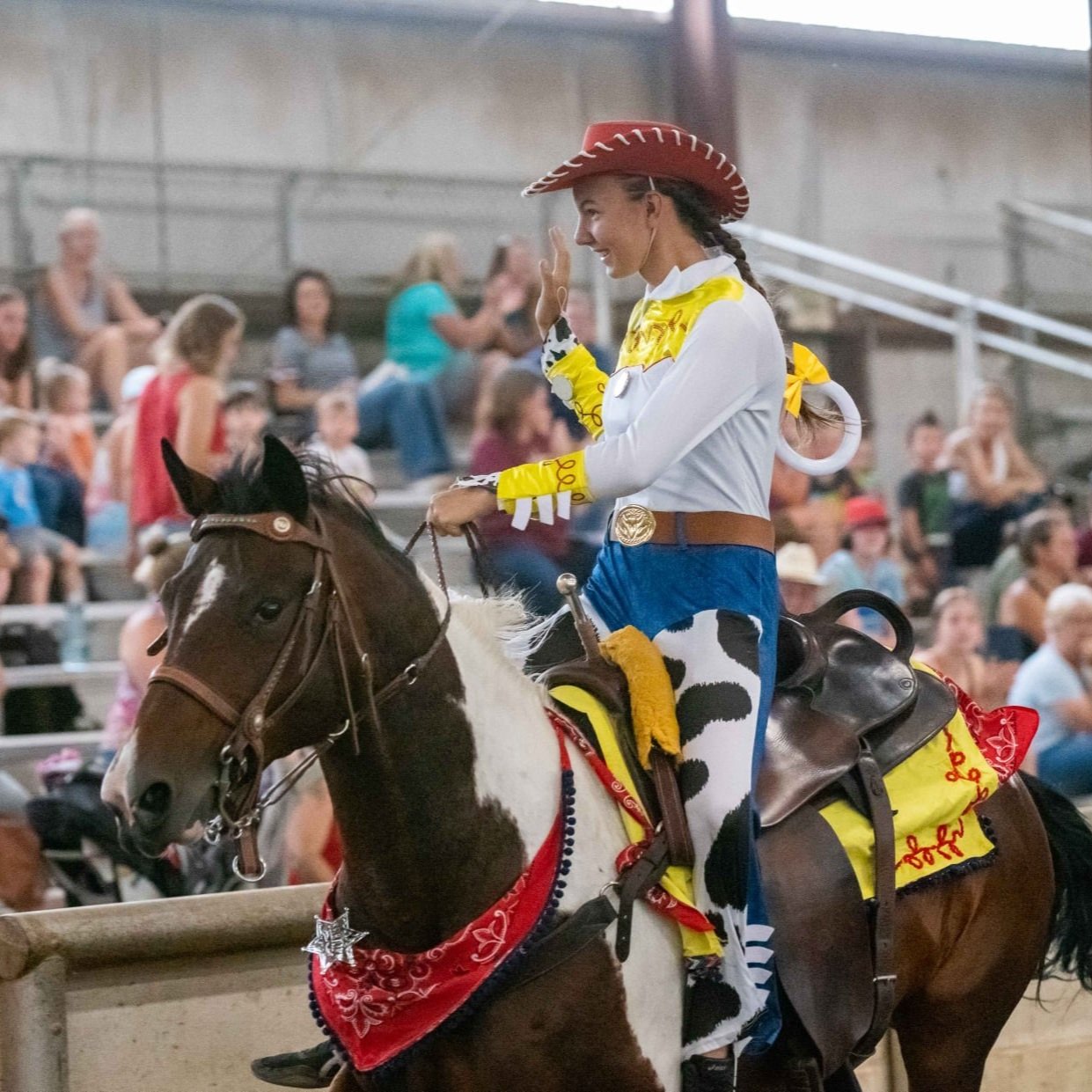 Rider on horseback waves to crowd in stands