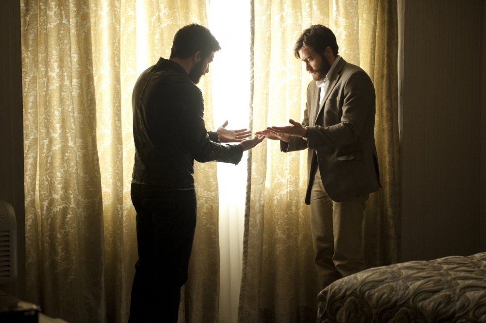 enemy-2013-001-anthony-and-adam-comparing-hands-behind-curtains.jpg