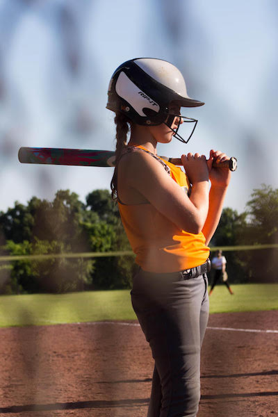 Lexi, a nine-year-old athlete with hearing loss, prepares to bat. Her helmet hides the processors she wears over her ears. Photo by Gina Bailey.