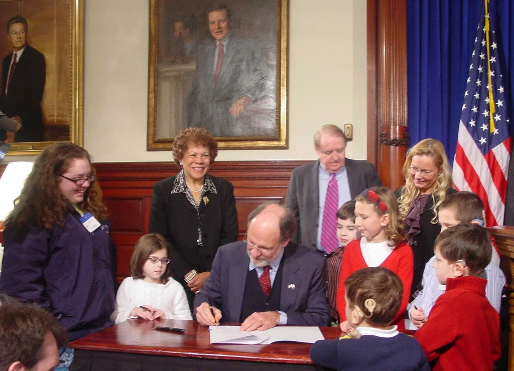 Grace Gleba (red sweater on right) looks on as HAIL is signed into law.