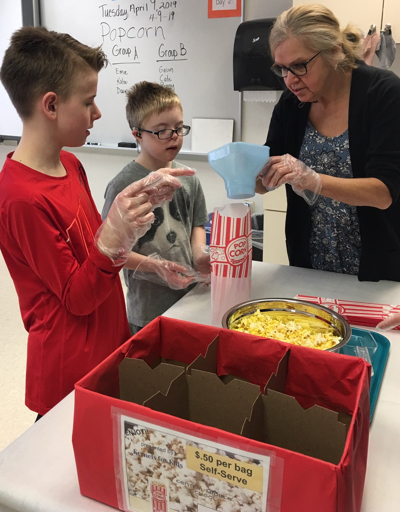 Lisa Olson (teacher) helping students prepare to bag popcorn. 4.8.19 clearance on record. - Copy.jpg