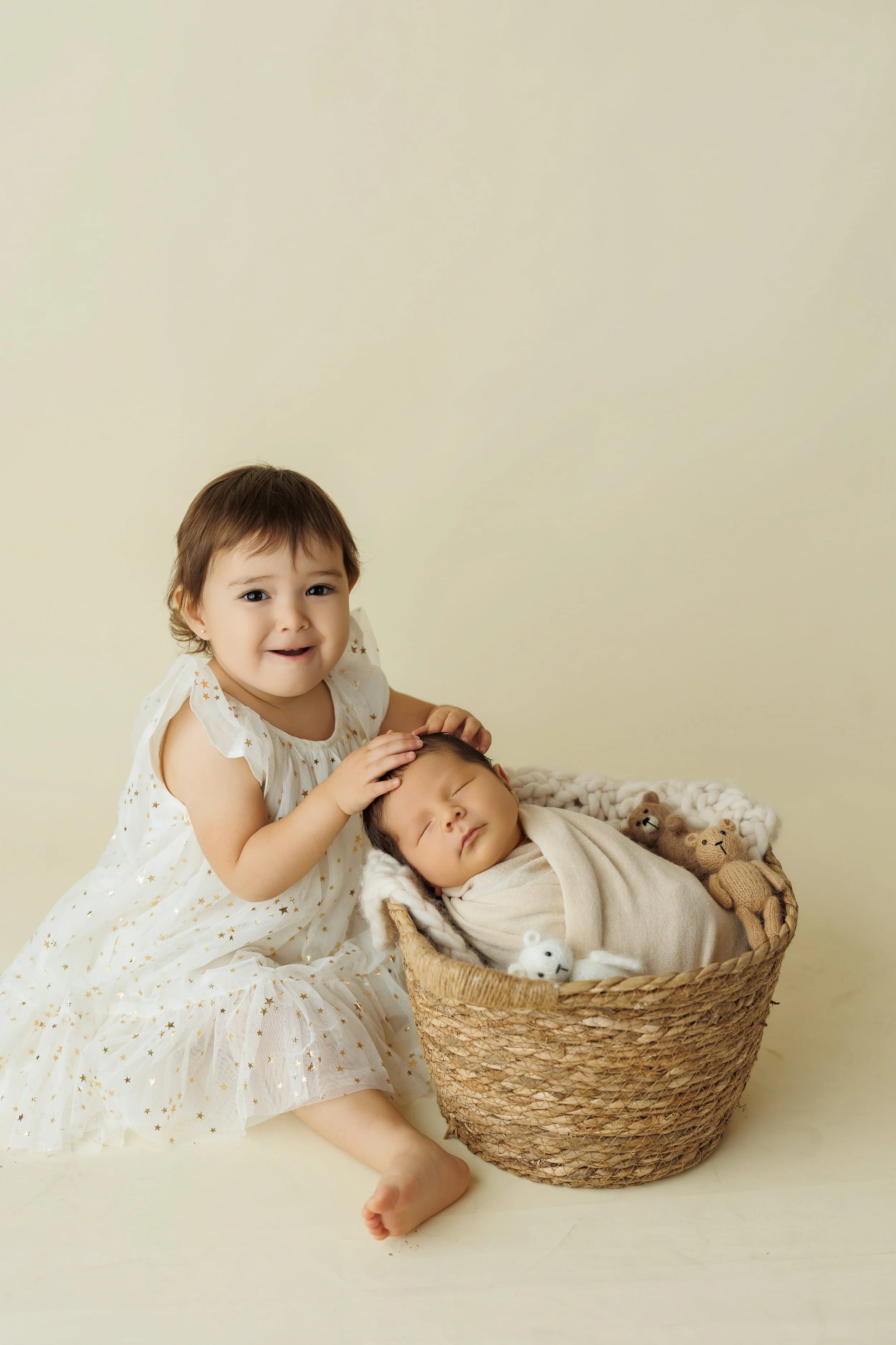 Wrapped newborn baby photographed in studio with toddler