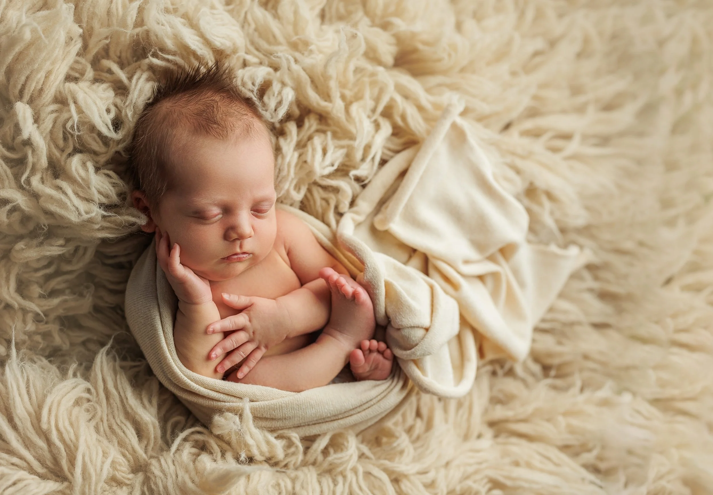 Sleeping newborn wrapped in soft textures