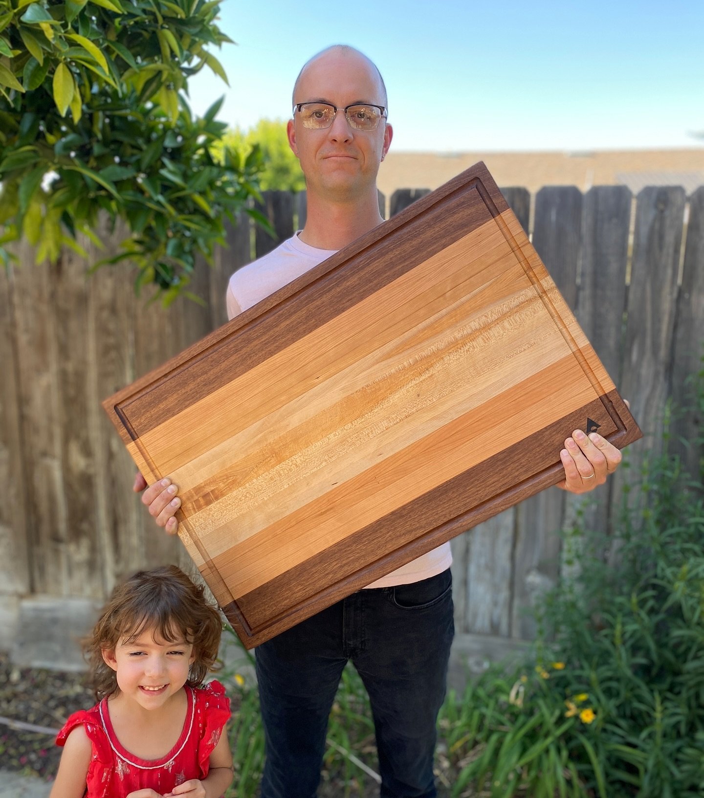 If you visit me at the shop, chances are my middle kid, Winnie, will run out and offer you a flower from our garden. Here I&rsquo;m holding a monster board of cherry, maple and black walnut moments before its inaugural service. I quite enjoy making t