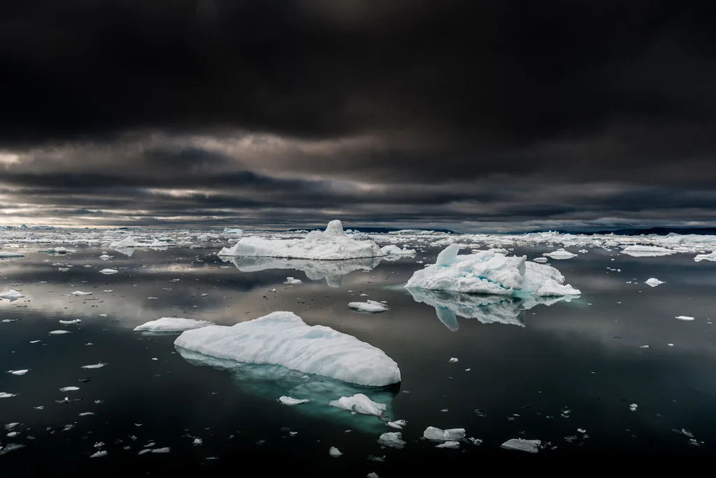 Dark skies and sea with icebergs floating by