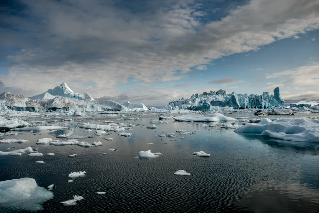 Icebergs floating out at sea ona sunny day with blue skies