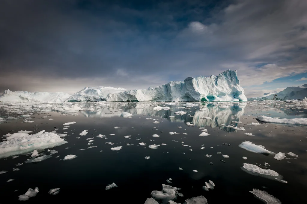 large iceberg with mirror reflection in dark water