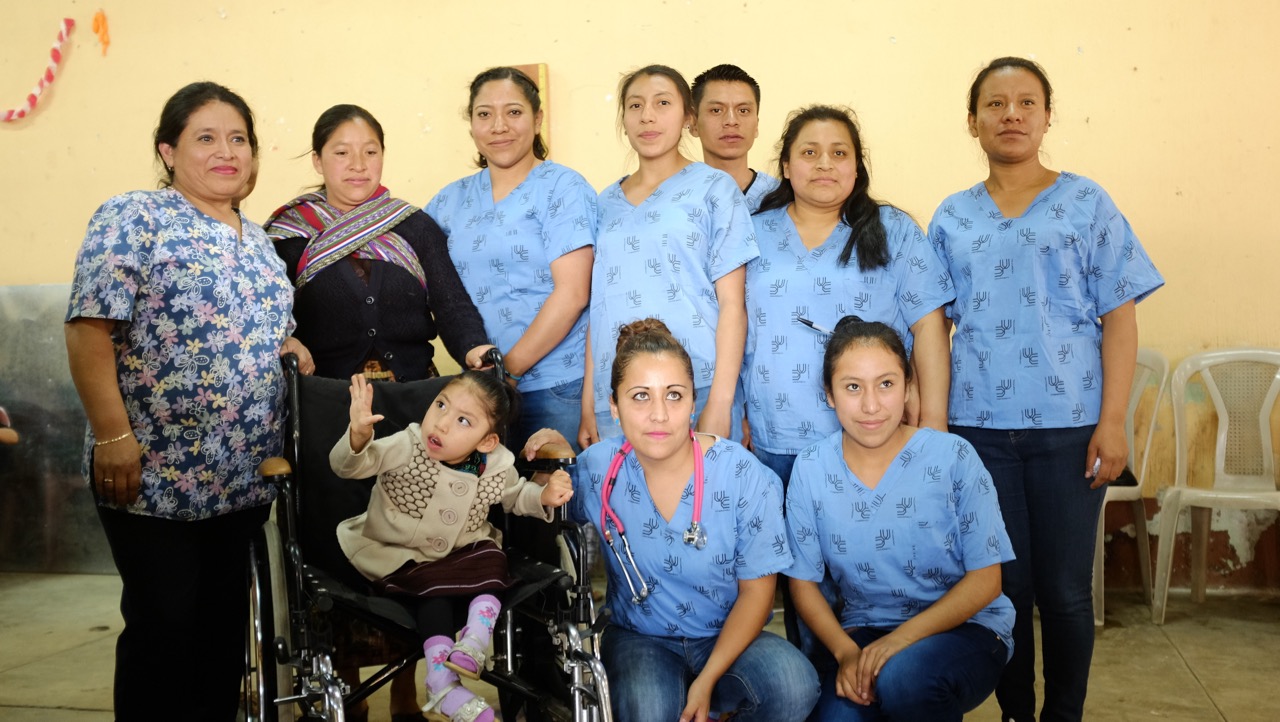 Iliana Sapón and her team of volunteers with the recipients of a wheelchair