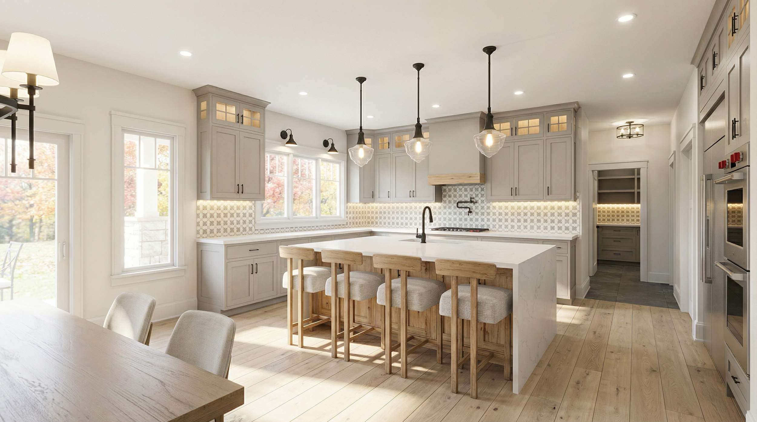 Modern kitchen with white cabinets, a large island with four wooden barstools, pendant lights above the island, and windows overlooking trees with autumn foliage.