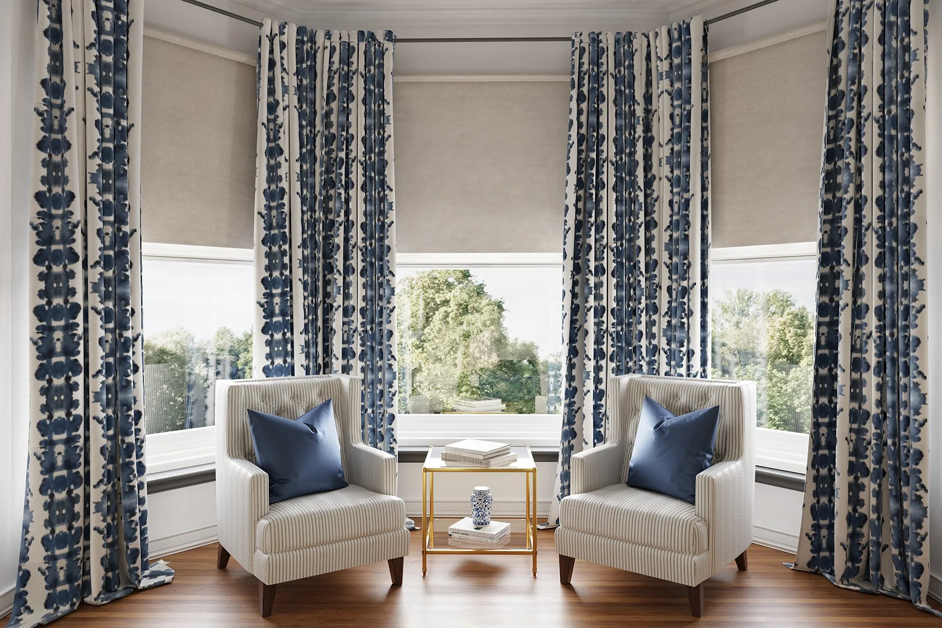 Floor-to-ceiling blue patterned curtains mounted near the ceiling and extending to lightly touch the hardwood floor in a bright bay window sitting area.