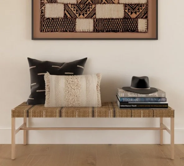 Neutral and black textured throw pillows styled on a woven bench in a California casual living room by virtual interior designer Joshua Jones of JJones Design Co.
