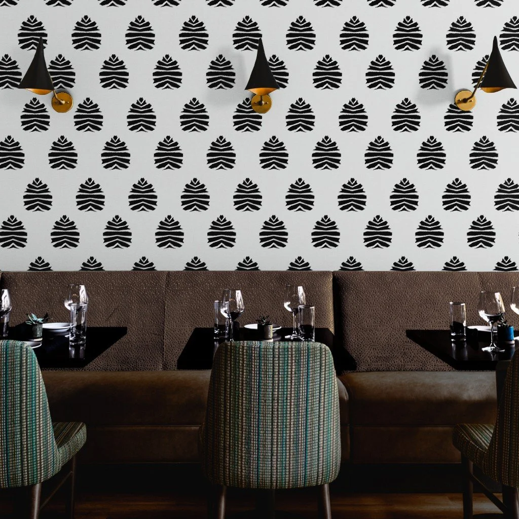 Spoonflower mockup showing “Abstract Pine Cones” wallpaper in black and white—pattern by Joshua Jones, displayed in a restaurant interior.