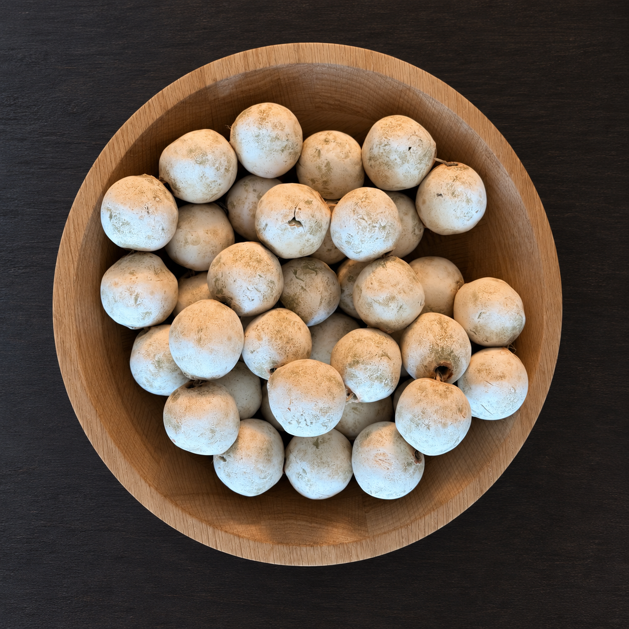 White patina decorative beads loosely arranged in a natural wood bowl on a black coffee table, styled by virtual interior designer Joshua Jones of JJones Design Co.