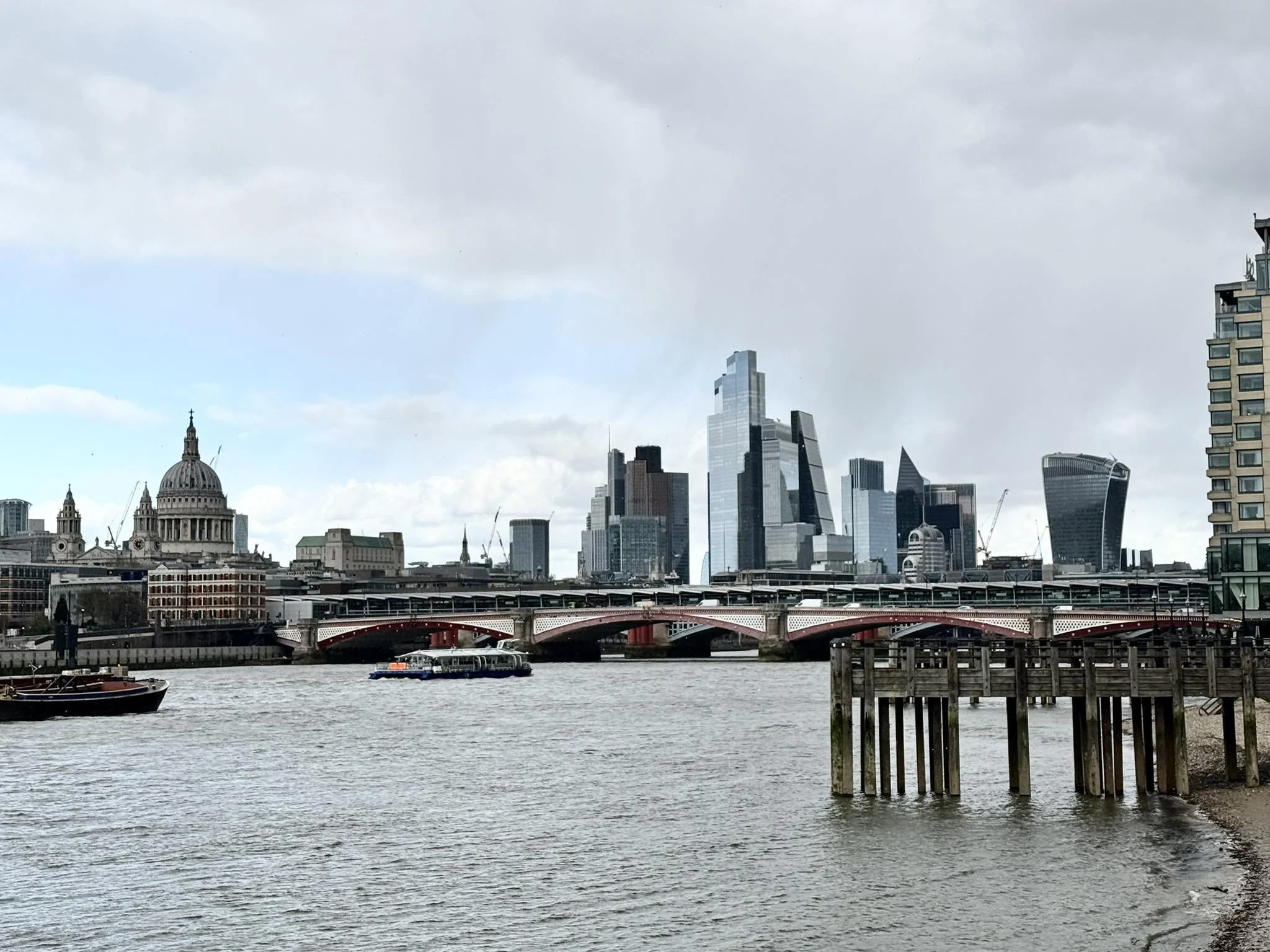 London skyline showing St. Paul’s Cathedral, modern skyscrapers in the financial district, and a bridge over the River Thames