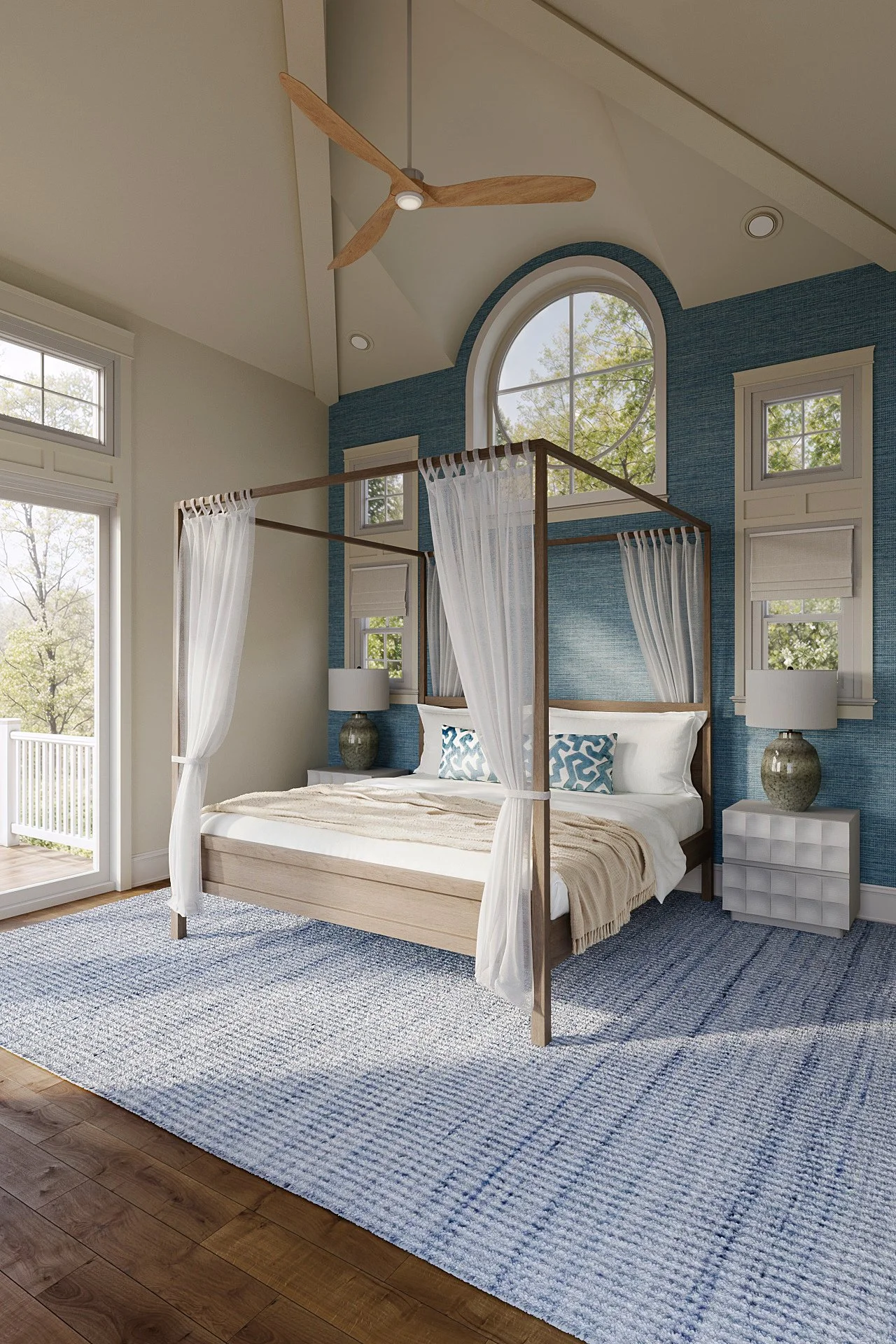 Modern coastal bedroom with a light wood canopy bed, layered white bedding, sheer curtains, blue accent pillows, textured area rug, and natural light, designed by Joshua Jones of JJones Design Co.