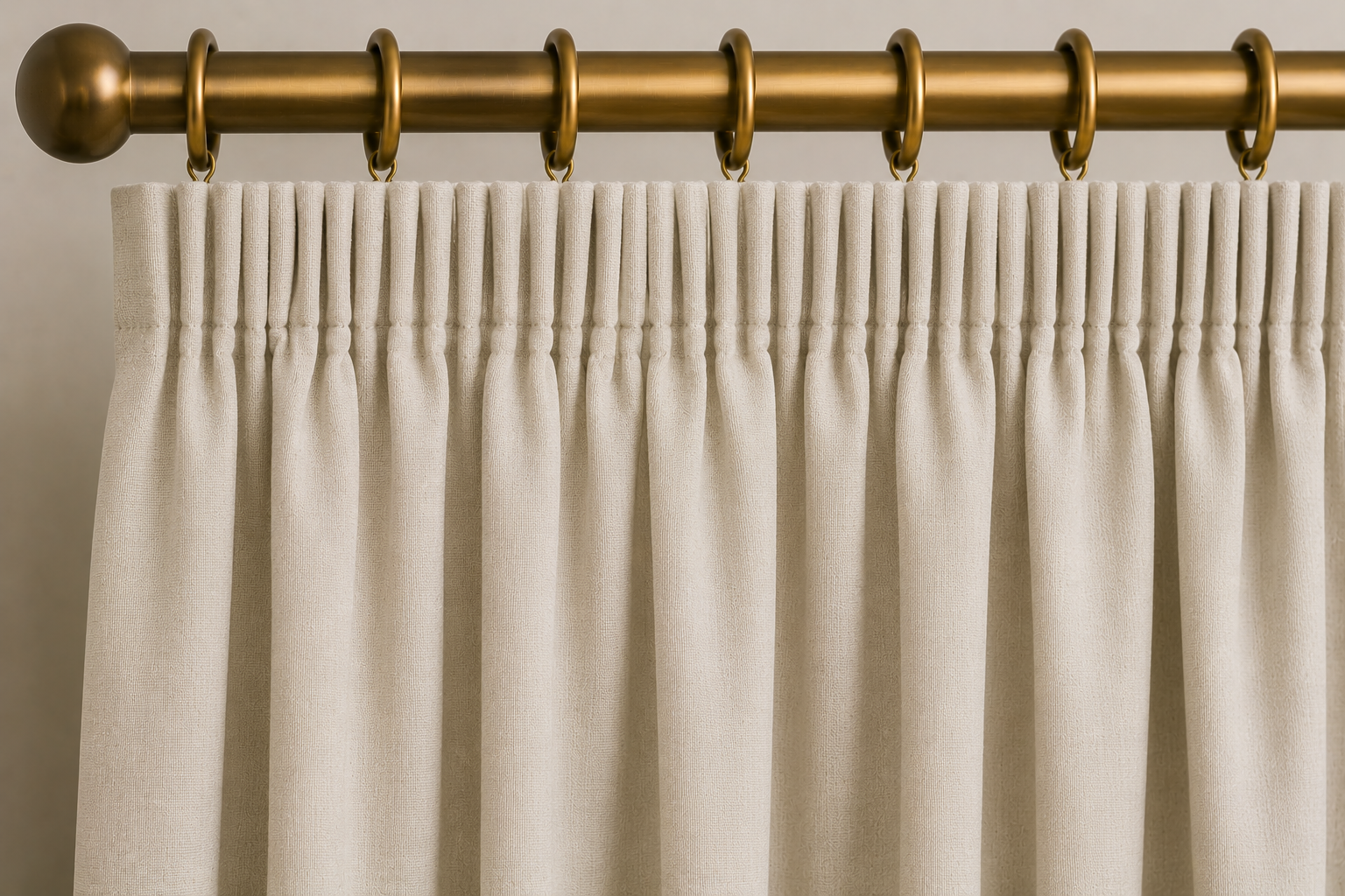 Close-up AI rendering of a cream pencil pleat drapery header attached to decorative curtain rings on an antique brass drapery rod, showing tightly gathered and closely spaced pleats across the top of the panel.