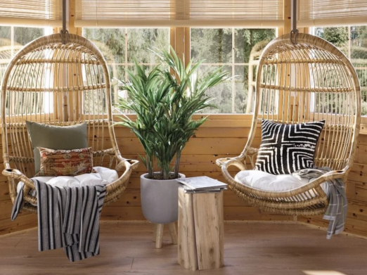 Boho hanging rattan lounge chairs styled with decorative throw pillows in a cozy sunroom designed by virtual interior designer Joshua Jones of JJones Design Co.