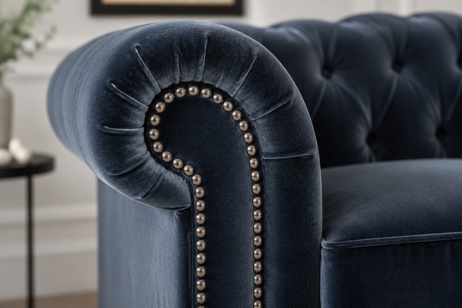 AI-generated close-up of a navy blue velvet Chesterfield sofa arm with nailhead trim, tufted upholstery, and a soft sheen highlighting the texture of the fabric.