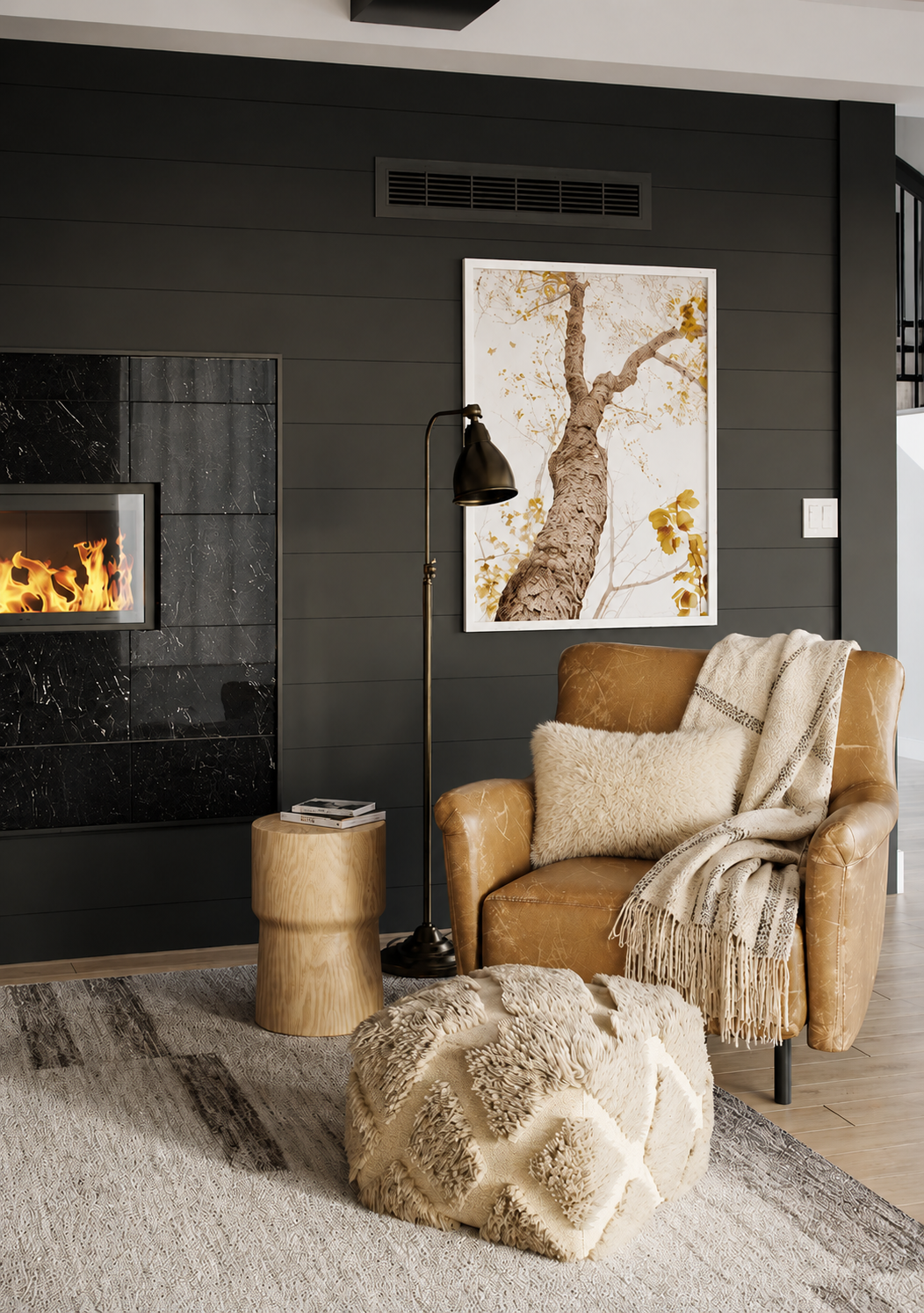 Scandinavian style living room with a caramel leather accent chair, handwoven throw blanket, ivory sheepskin pillow, black fireplace feature wall, wood side table, floor lamp, and textured pouf.