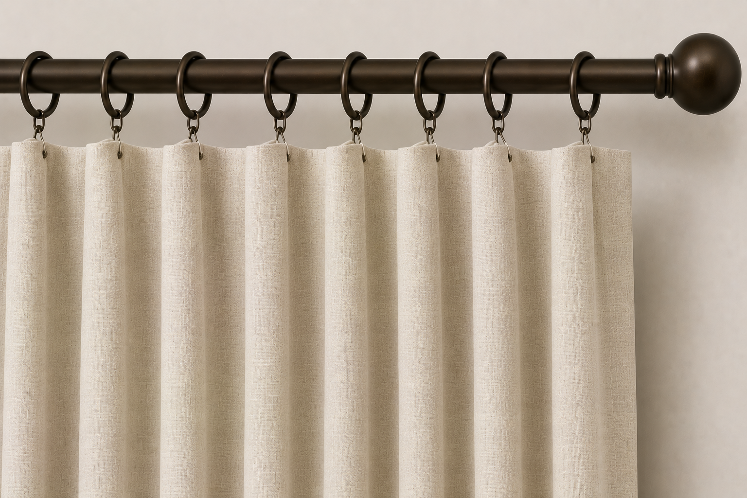 Close-up AI rendering of cream ring top drapery hung from dark bronze decorative rings with side clips attached to the edges of the fabric panel, creating soft, evenly spaced folds below a decorative drapery rod.