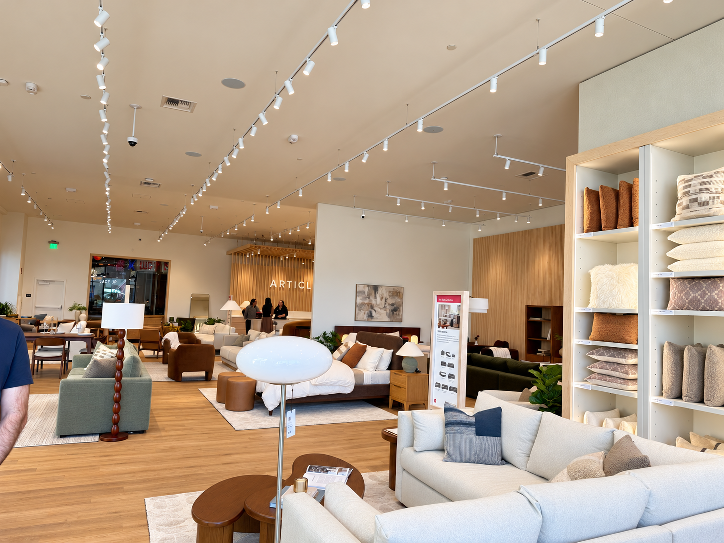 Wide view of Article’s Bellevue showroom with cream sofas, wood accent tables, floor lamps, a styled bed, and shelves of decorative pillows.