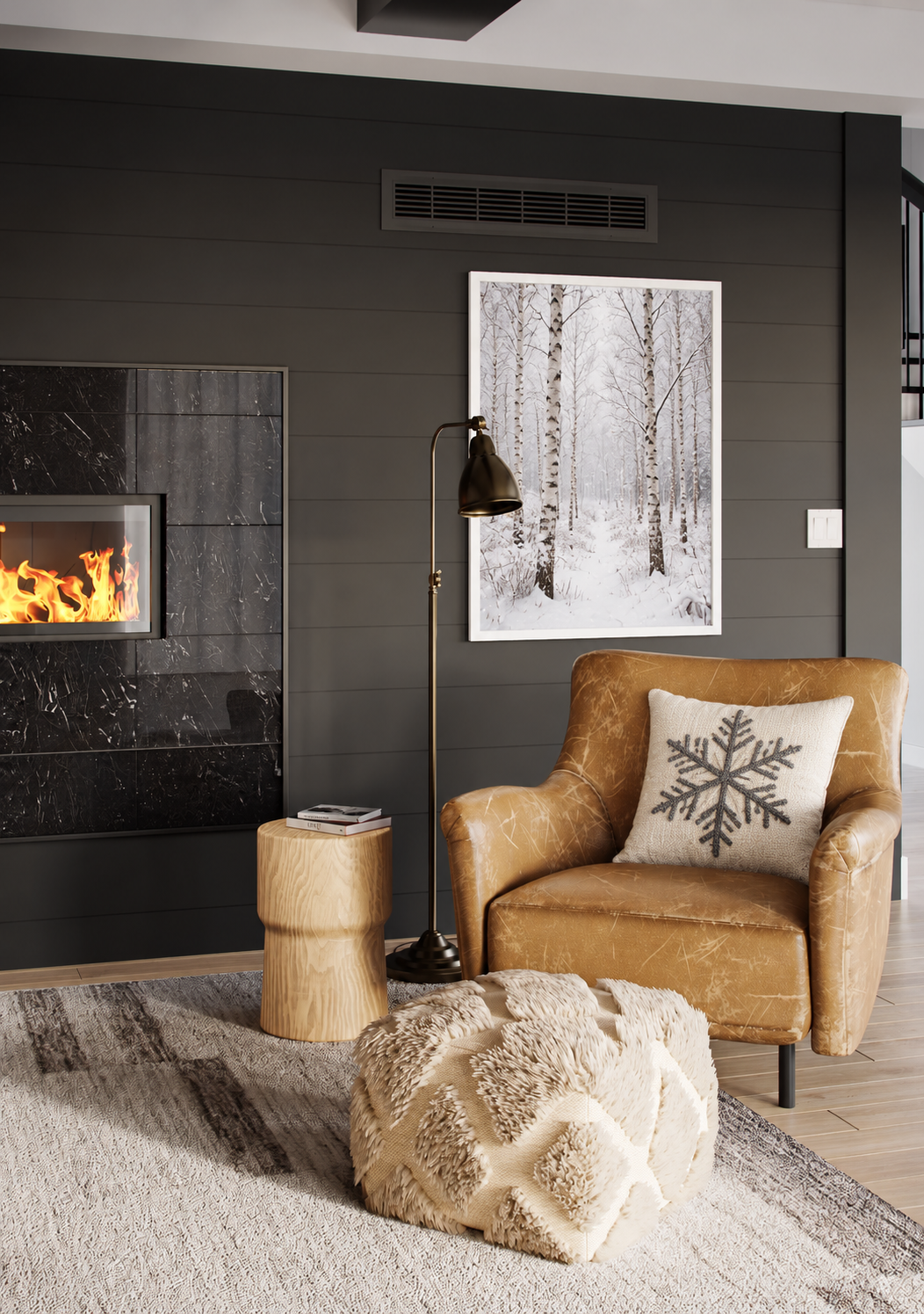 Framed snowy birch forest artwork above a caramel leather chair with an ivory snowflake pillow, beside a black marble fireplace and oak side table.