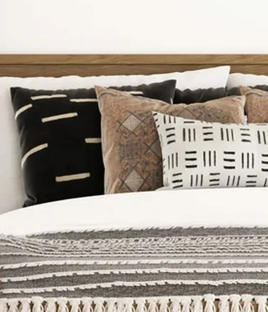 Layered black, tan, and patterned throw pillows arranged on a bed in a California casual bedroom designed by virtual interior designer Joshua Jones of JJones Design Co.