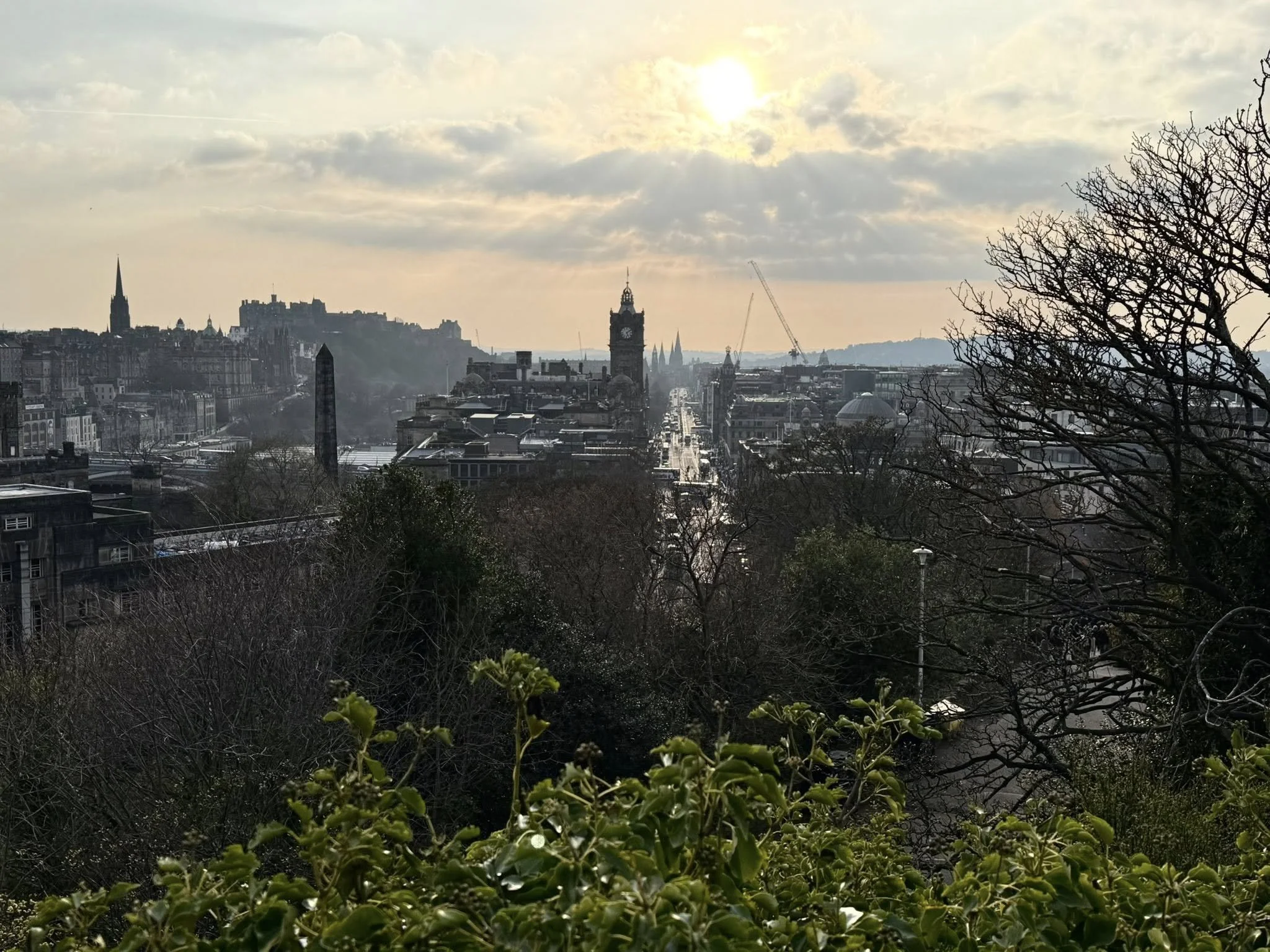 Edinburgh city view from Calton Hill at sunset, with historic buildings, clock tower, and Edinburgh Castle in the distance
