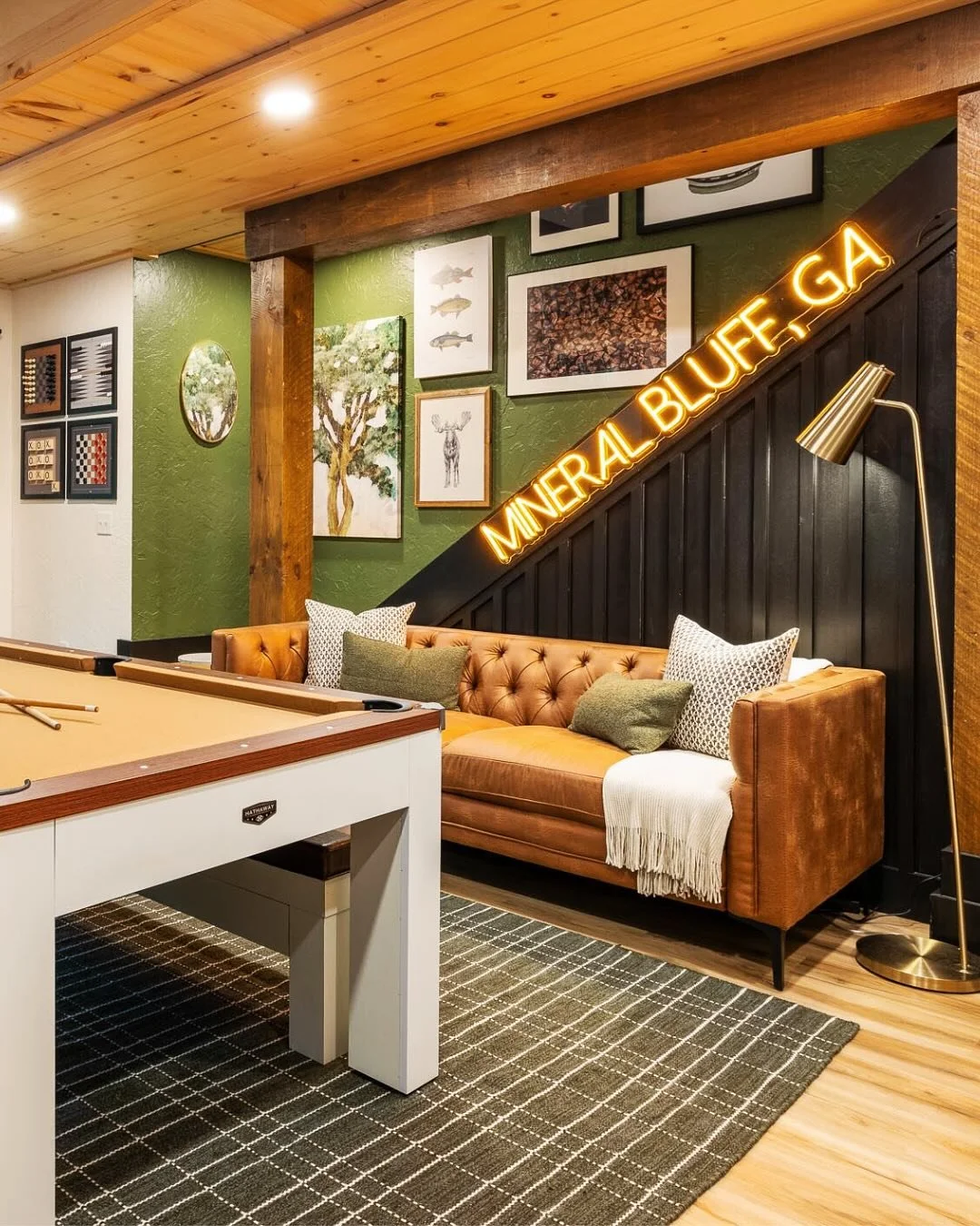 Custom "Mineral Bluff, GA" neon sign displayed in a game room with a pool table and lounge seating.