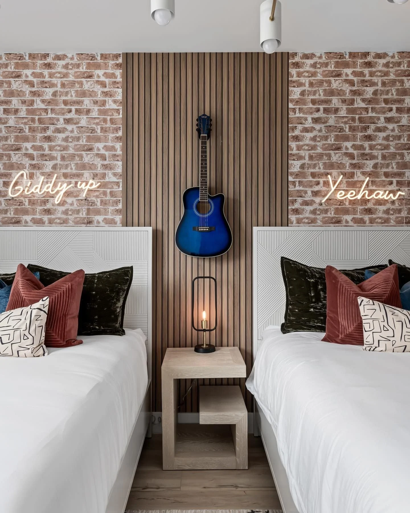 Pink "Giddy Up" and "Yeehaw" neon signs displayed in a western-inspired bedroom.