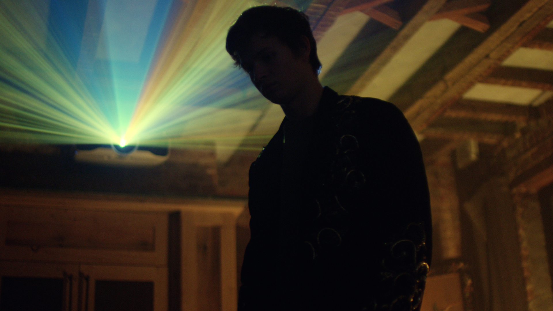 Ansel Elgort in silhouette, backlit by a projector beam