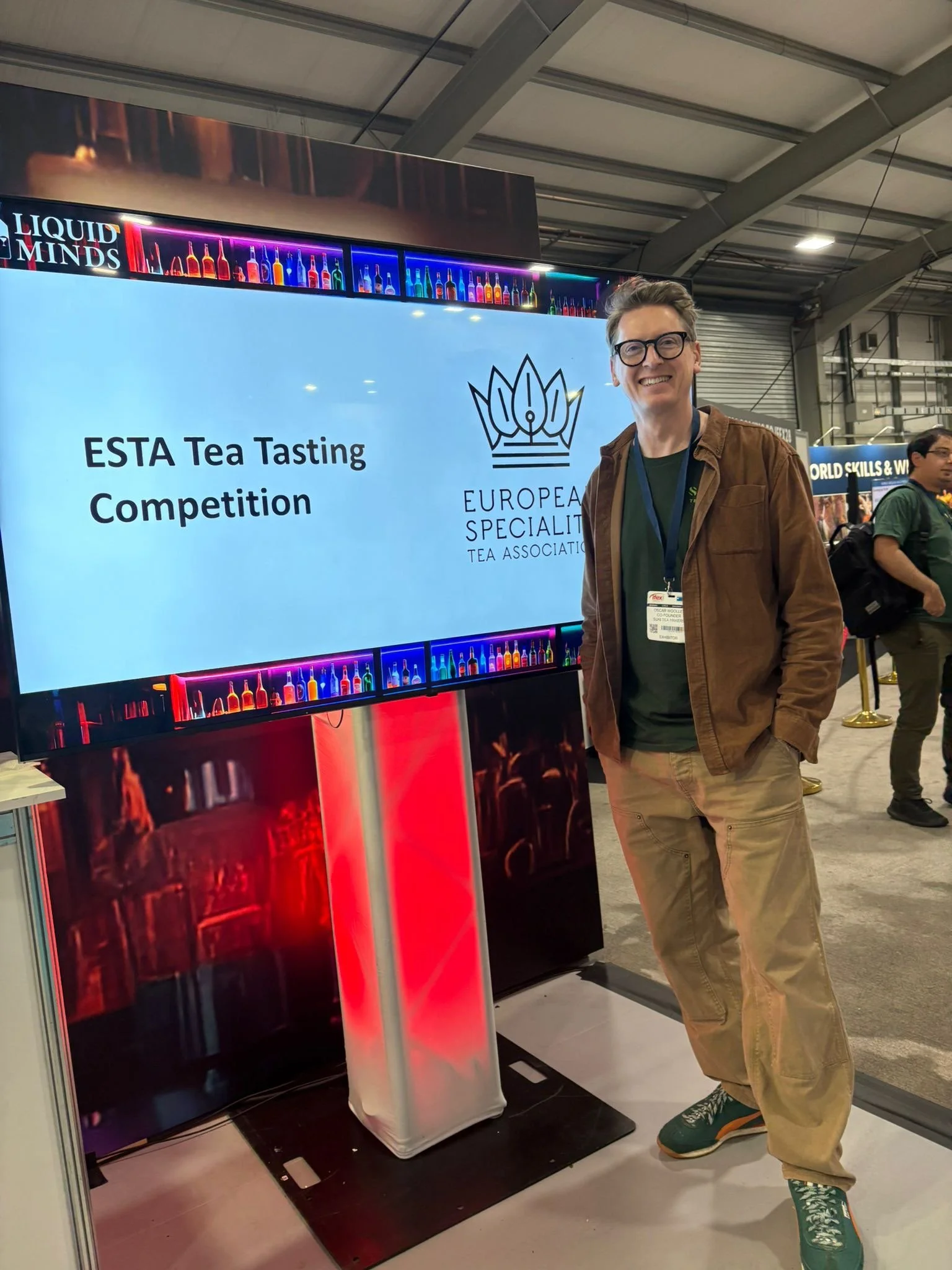 Oscar in front of a screen displayin "ESRA Tea Tasting Competition and ESTA's logo