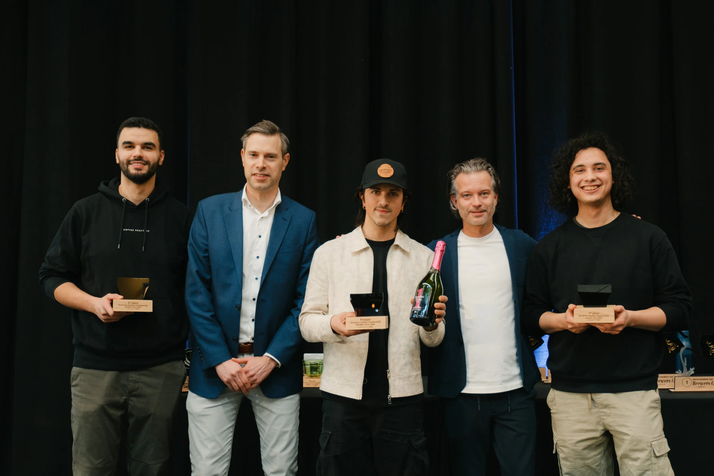 Five people, thre of them are the winnes holdimg a trophy