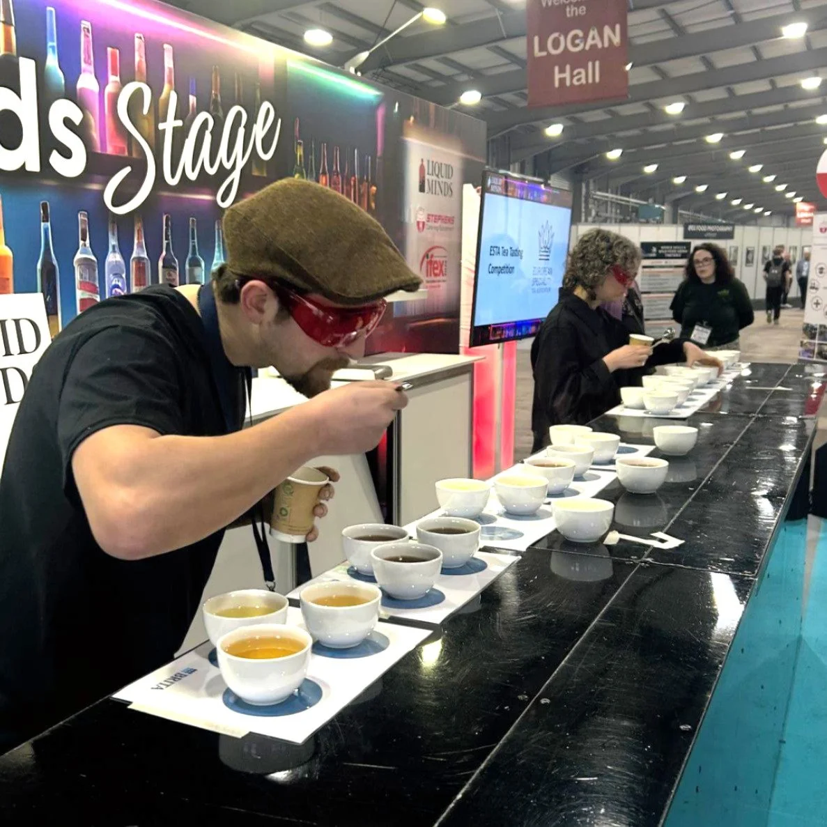 People tasting different cups wearing red glasses