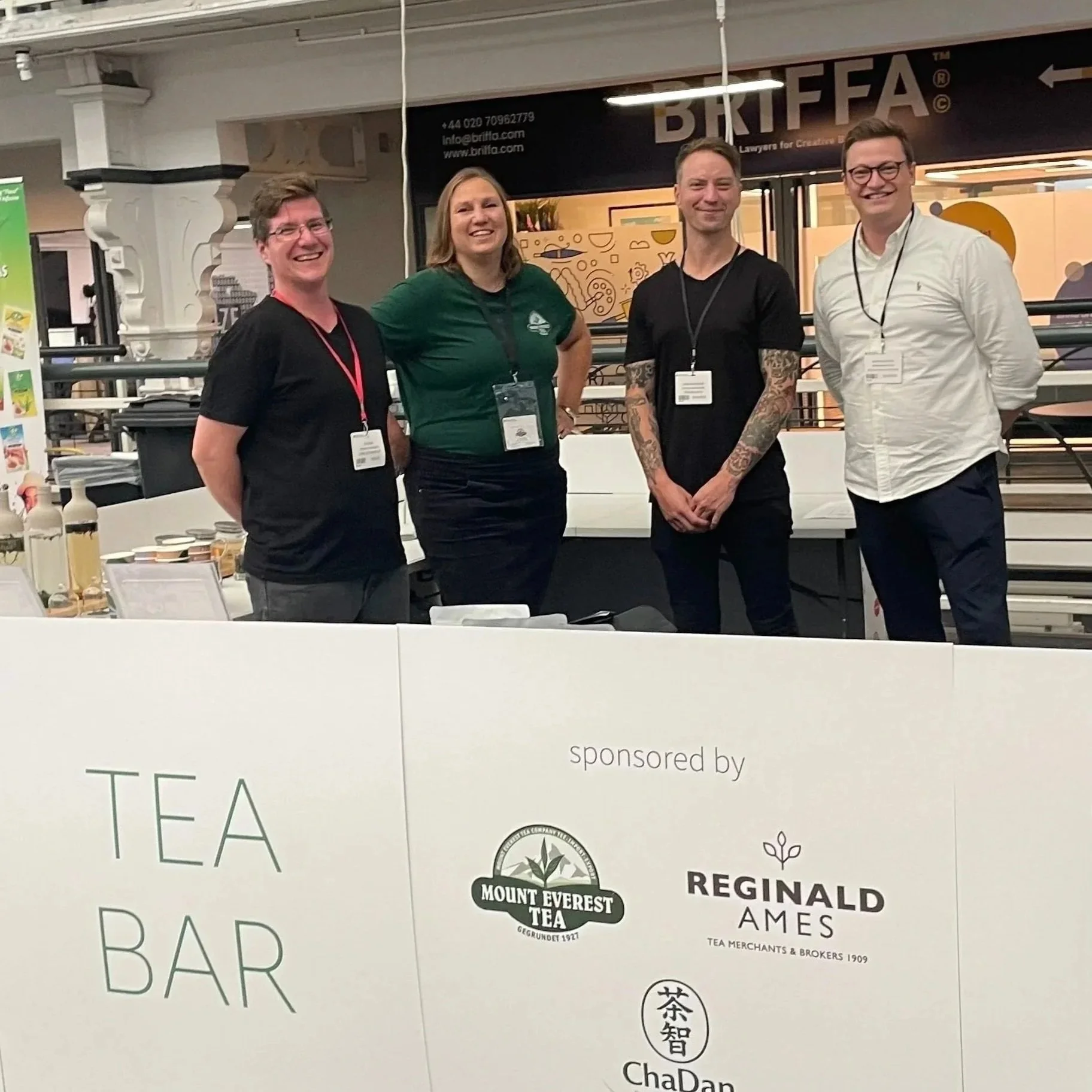Four people standing at the Tea Bar stand