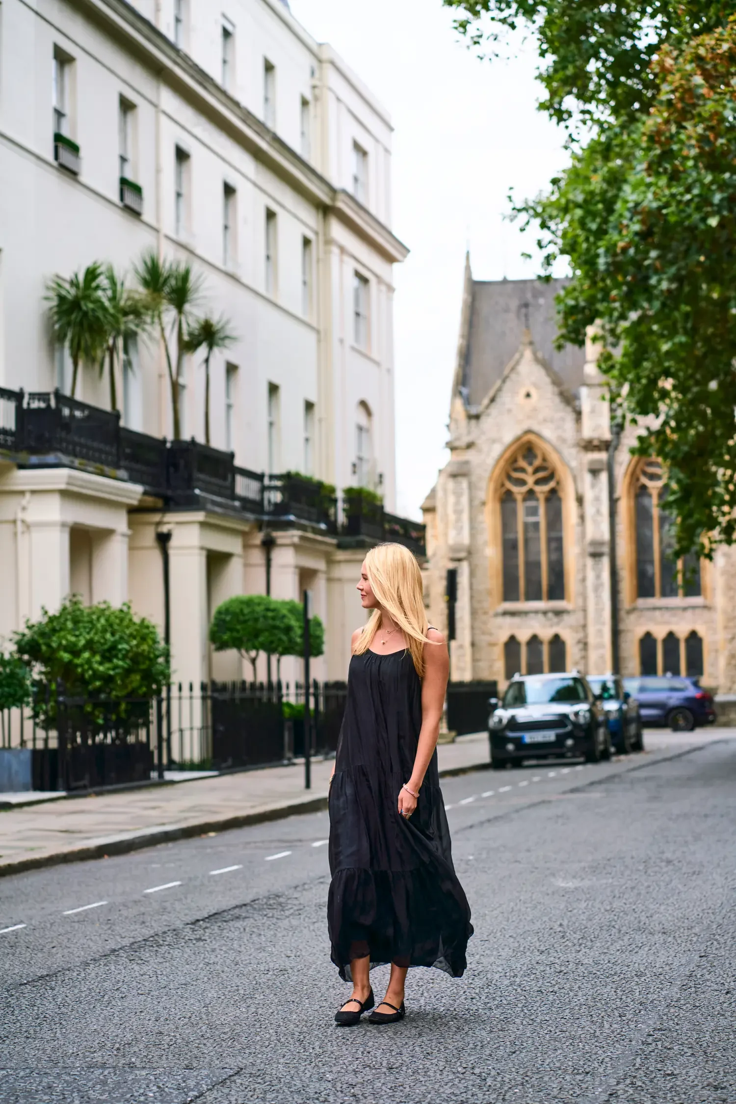 Woman in a long black dress on a white stucco street in Belgravia, London