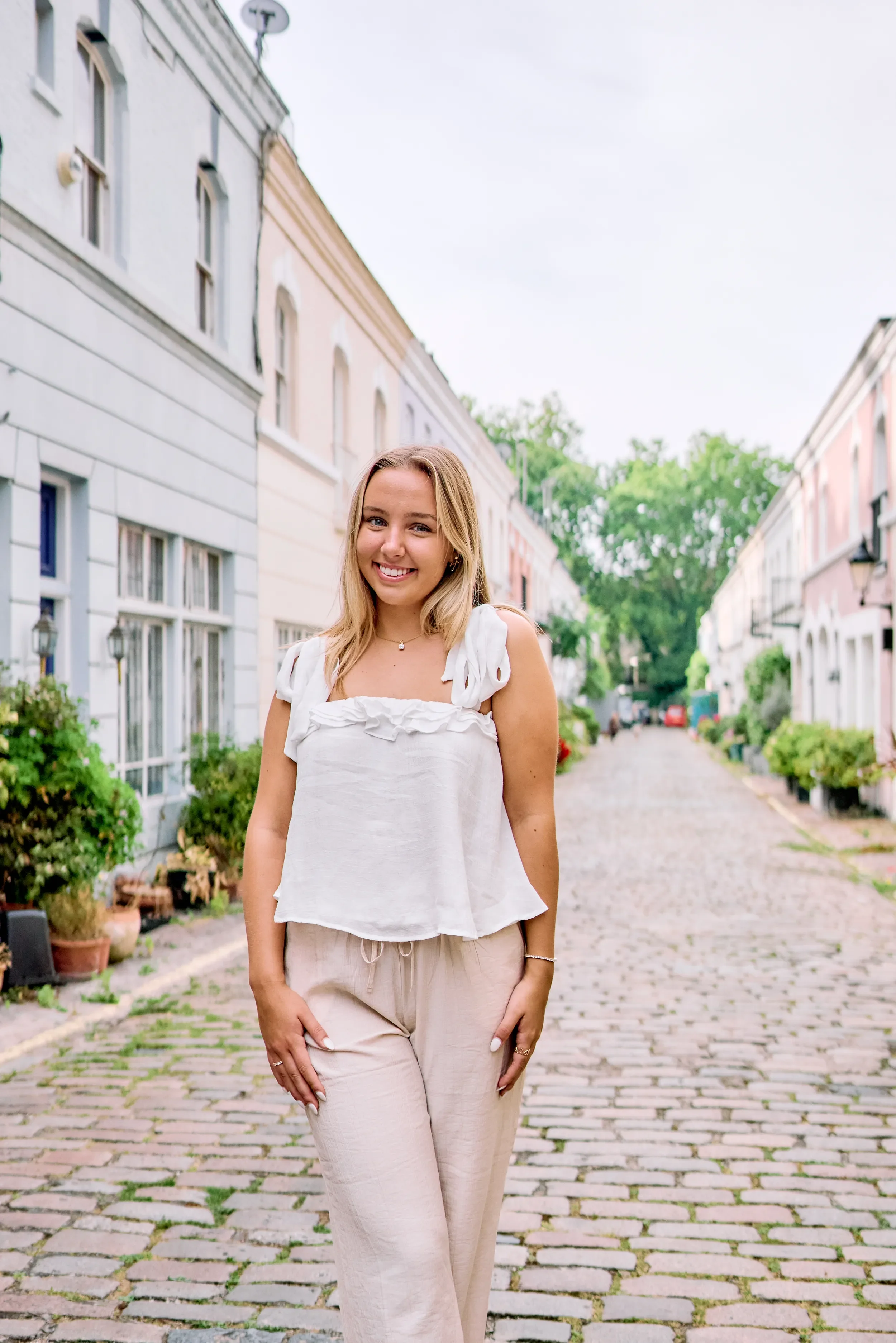 High school senior portrait on a cobblestone mews street lined with pastel houses in Kensington, London
