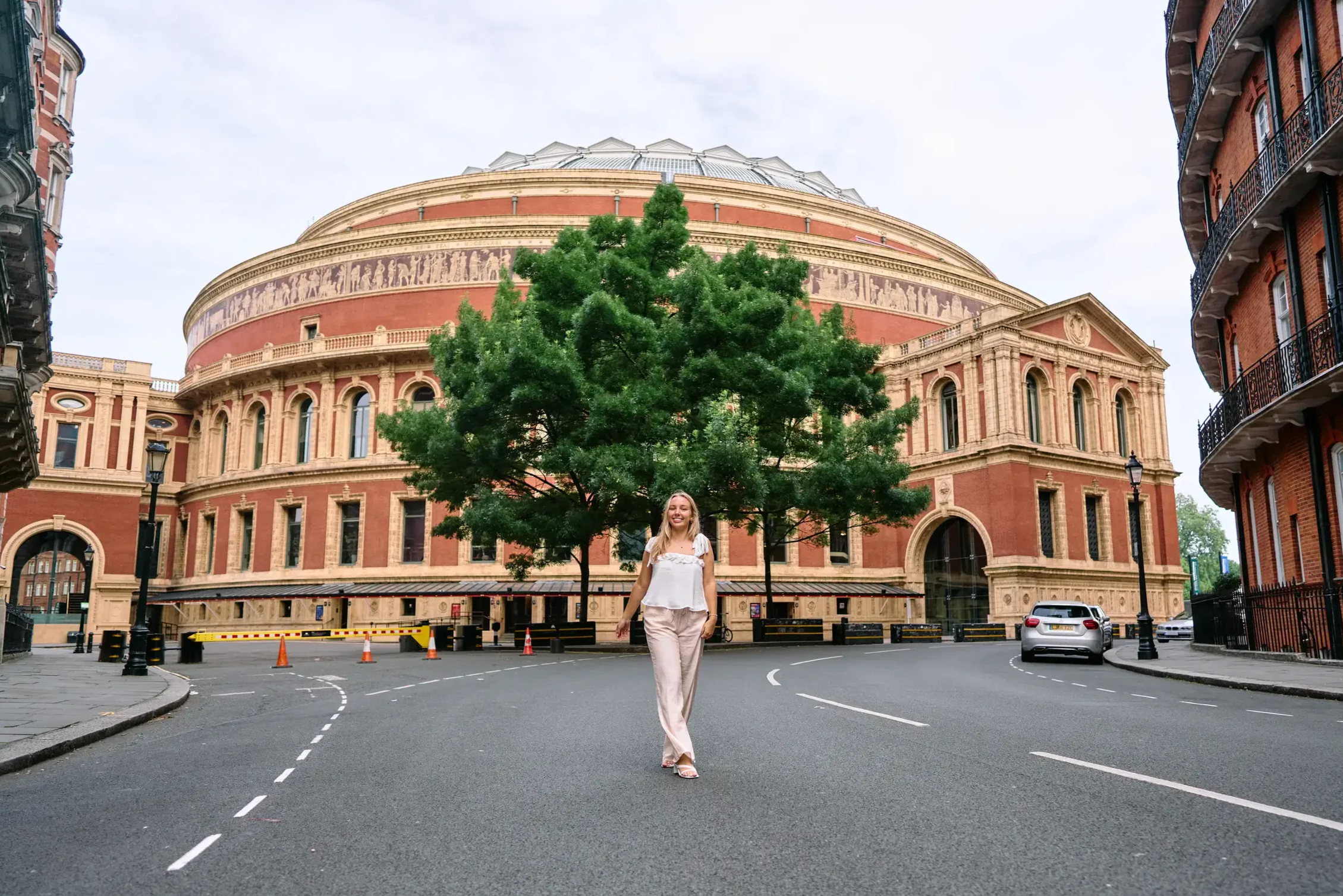 High school senior walking towards the camera with the Royal Albert Hall in the background during a portrait photoshoot in Kensington, London