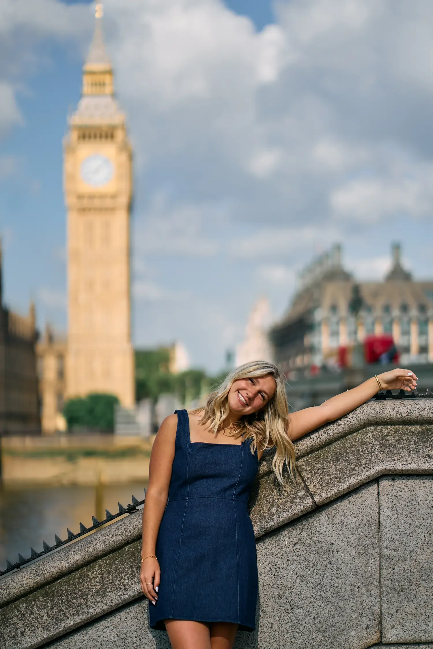 Senior portrait leaning on the Westminster Bridge balustrade, with Big Ben and the red buses behind her