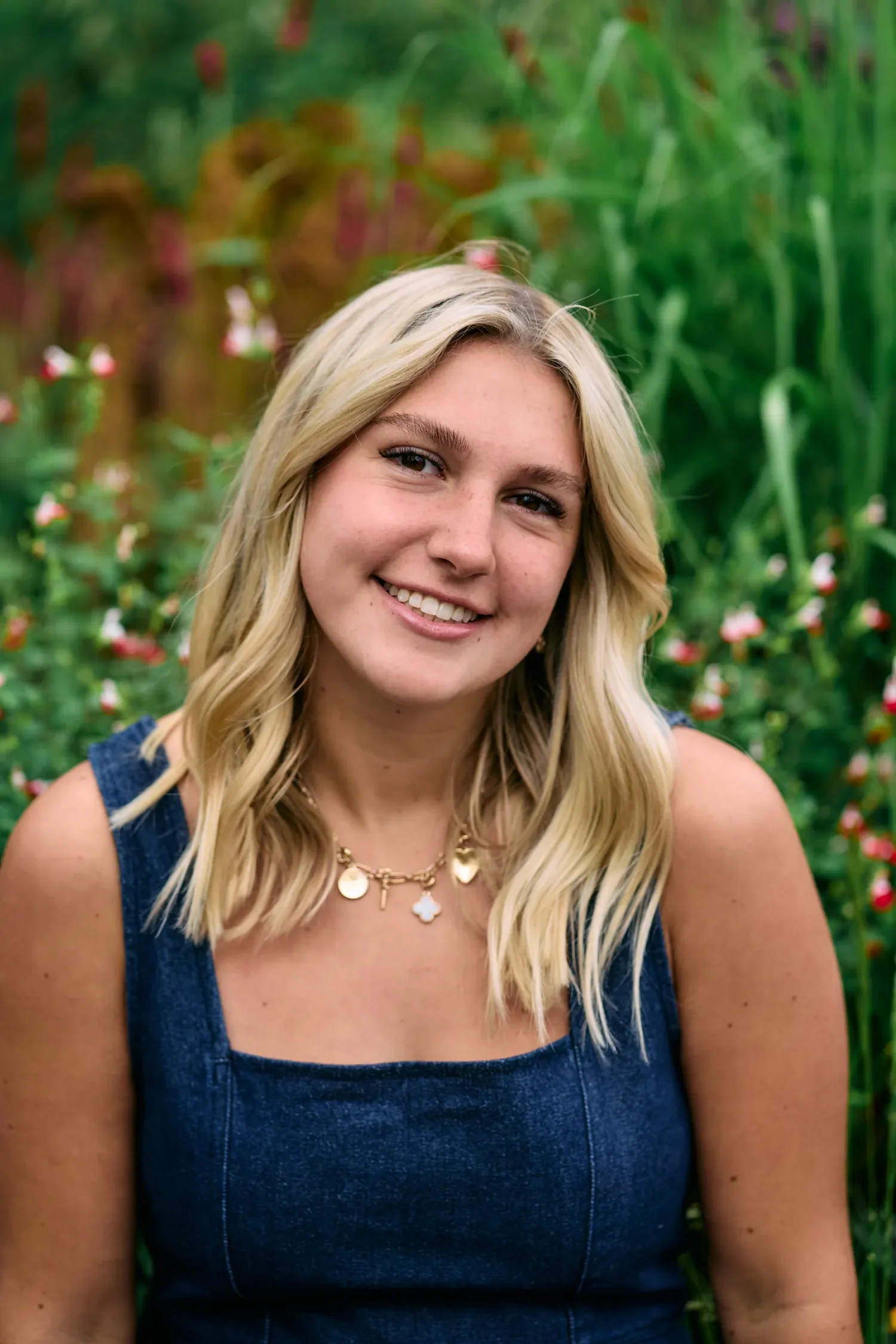 Senior portrait among flowers on South Bank, wearing a navy denim dress