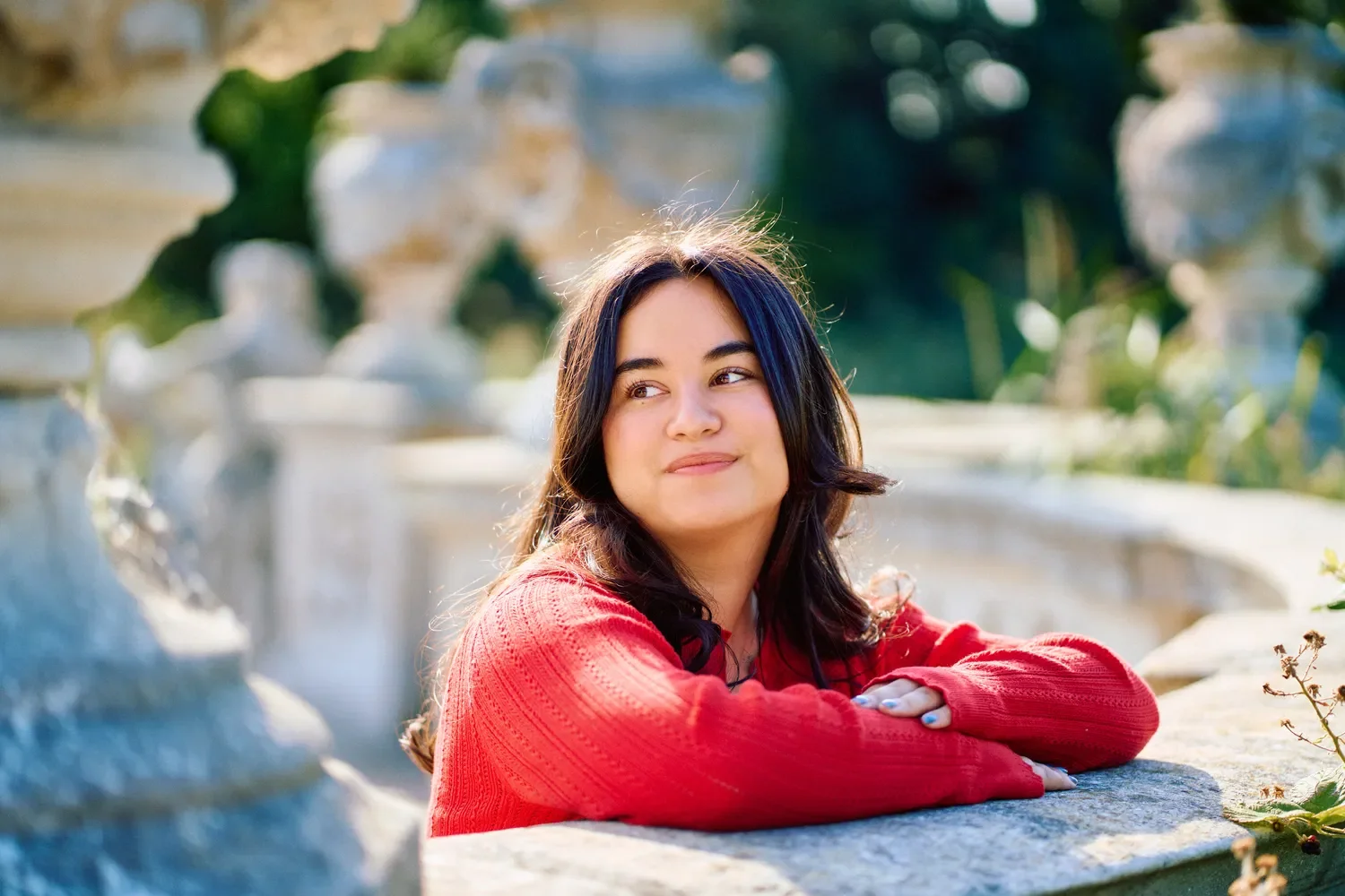 Teenage girl in a red top leaning on a stone fountain wall in Hyde Park, London